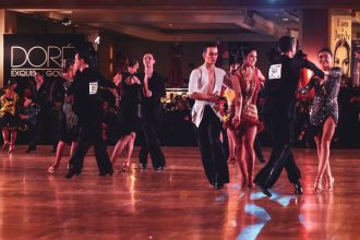 Casal executa uma coreografia de dança de salão em um palco iluminado.