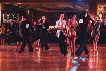 Casal executa uma coreografia de dança de salão em um palco iluminado.