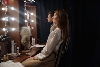 Dois atores sentados em um camarim de teatro, revisando roteiros antes de uma apresentação.