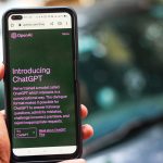 Pessoa segura um smartphone que exibe a página do ChatGPT no site da OpenAI.